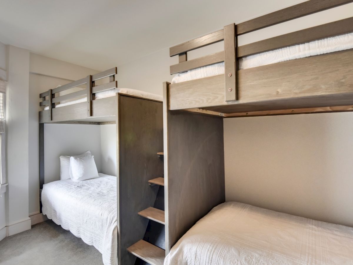 The image shows a bedroom with two bunk beds, each consisting of a lower bed and an upper bed accessible by a small ladder in the middle.