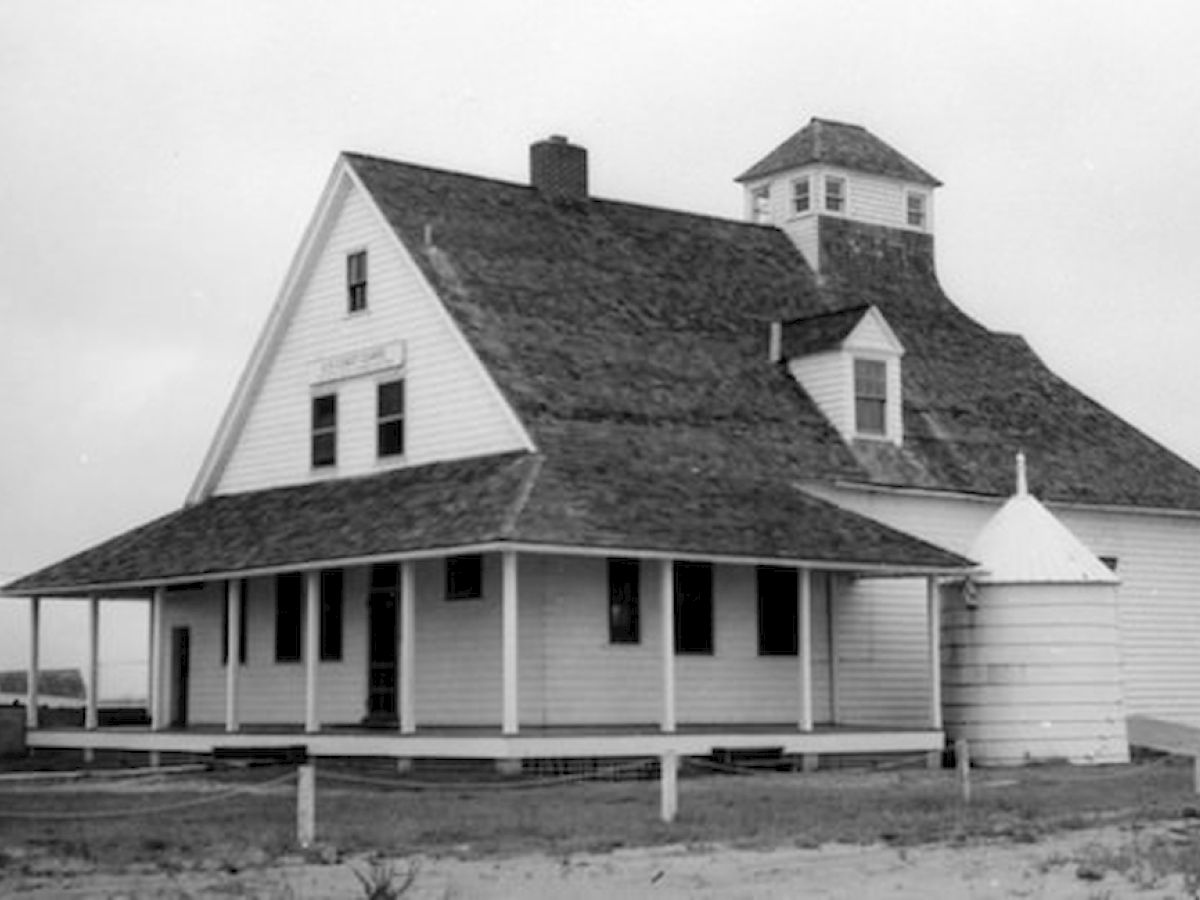 The image depicts a historic farmhouse with a unique roof design, a small tower, and a wrap-around porch, standing in a rural setting.