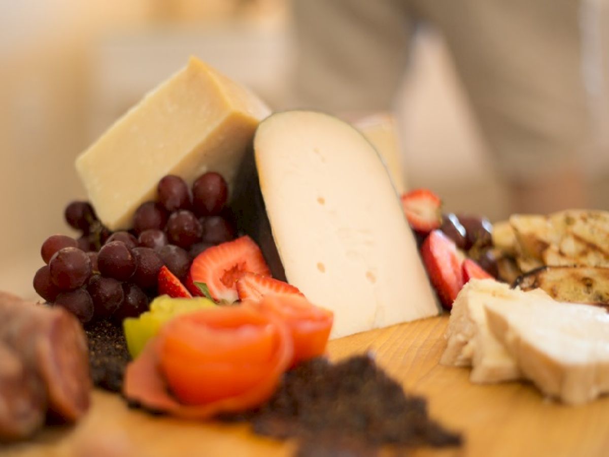 This image shows a charcuterie board with various cheeses, grapes, strawberries, sliced meats, and crackers.