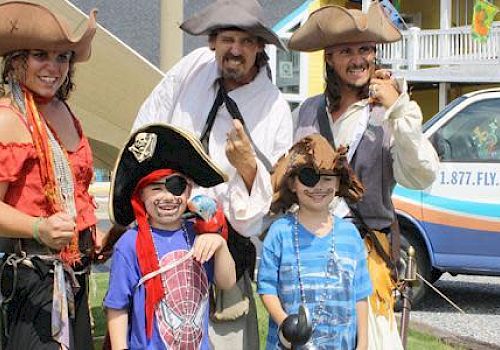 People dressed as pirates, including children with eye patches, posing for a photo. A van labeled 