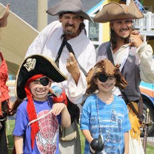 People dressed as pirates, including children with eye patches, posing for a photo. A van labeled 