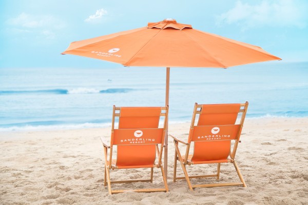 Two orange lounge chairs facing the water.
