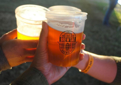 Three hands holding plastic cups of beer with a logo that reads 