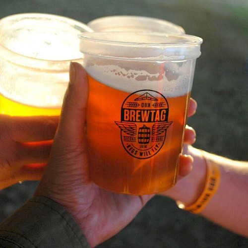 Three hands holding plastic cups of beer with a logo that reads 