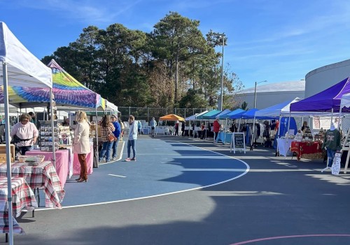 People are attending an outdoor market with various booths and tents under a clear blue sky.