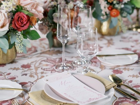 A beautifully set table with floral arrangements, elegant tableware, and a patterned tablecloth.